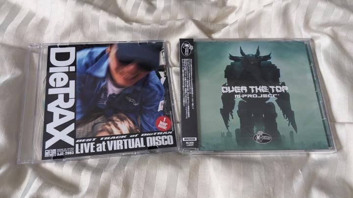 Two CDs placed next to each other on the bedsheet