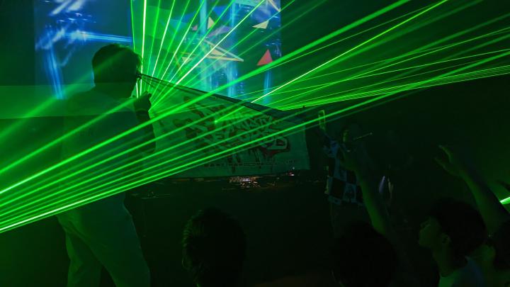 A group of people on the stage holding a flag with Dynasty Records graffiti-styled writing on it