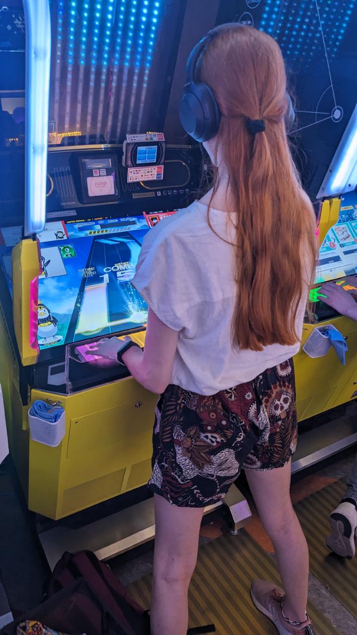 Kyuko playing an arcade game called Maimai DX