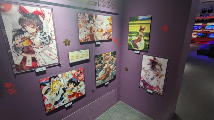 Works depicting Reimu Hakurei drawn by different artists hanging on the wall