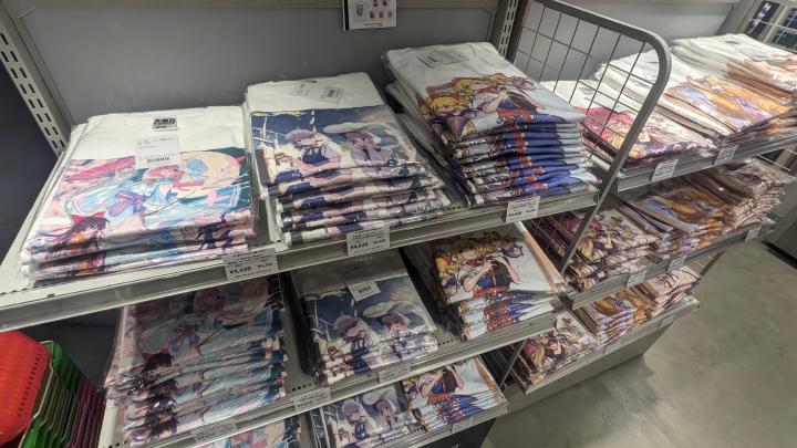 Store shelfs full of white t-shirts with illustrations depcting Touhou characters printed on.